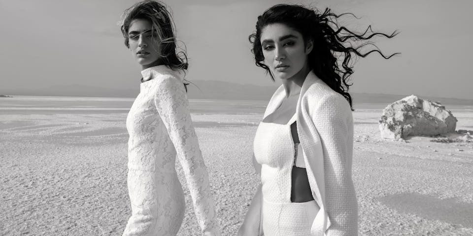 Diverse women in stylish outfits holding hands in desert