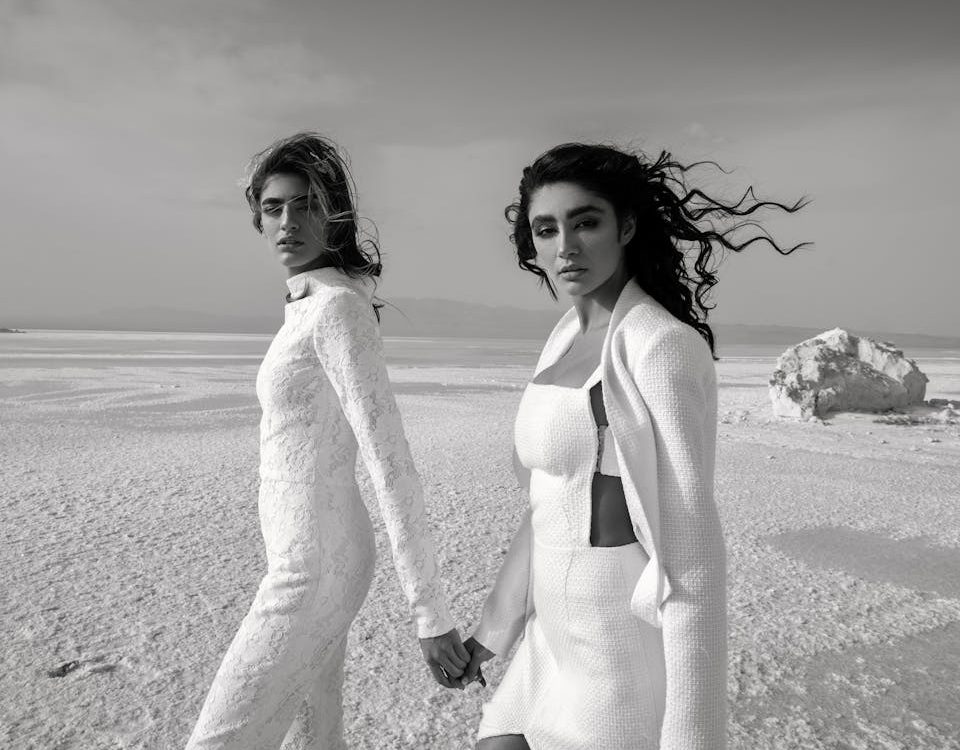 Diverse women in stylish outfits holding hands in desert